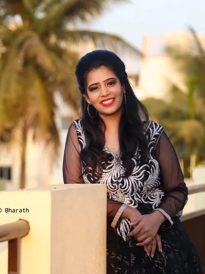 A relaxed portrait of the model on a rooftop, with palm trees and a soft sky in the background.