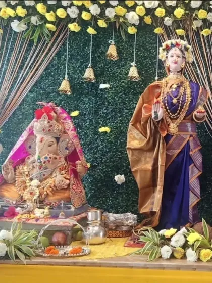 I also create special setups for Gauri Ganpati. This decor features a green backdrop with yellow and white floral arrangements, hanging bells, and pampas grass accents, creating a harmonious and traditional space for both deities.