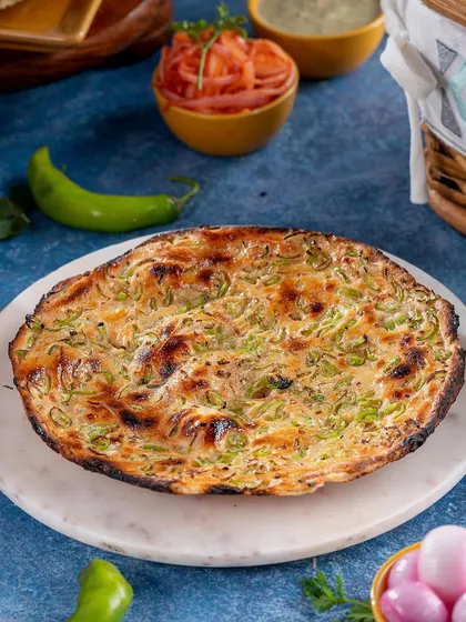 This unique Chilli Naan is the hero of the shot. The vibrant green of the chillies stands out against the charred, fluffy bread, creating a visually exciting image that promises a spicy kick.