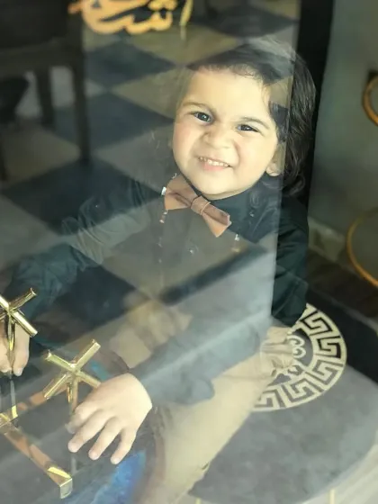 A playful shot from the kids' editorial for Hello! Uttarakhand Magazine. Even through the glass, you can see the sharp styling of the black shirt and bow tie.