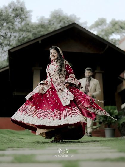 A joyful shot of the bride twirling in her stunning red lehenga, her happiness radiating from the photo.