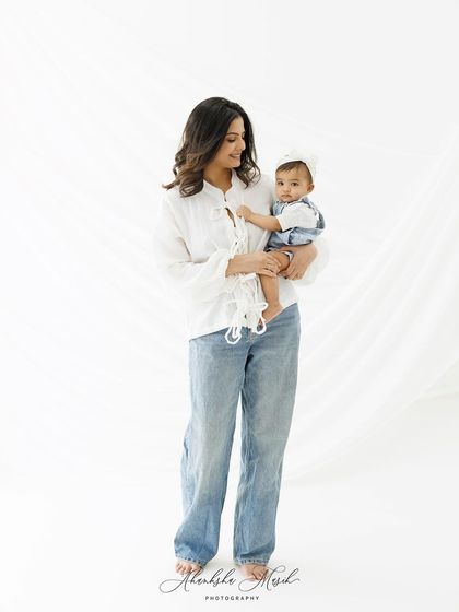 A full-length shot of this casual mother-daughter duo. The clean, bright background and simple styling create a fresh and modern family portrait.