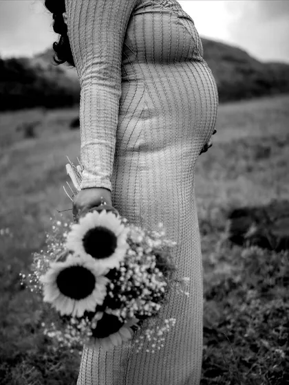 A black and white close-up focusing on the baby bump and the bouquet of sunflowers. It's an artistic and timeless shot that celebrates the beauty of new life.