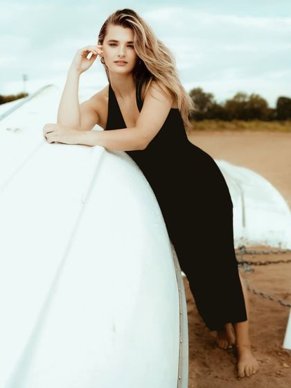 A classic beauty shot on the beach, with the model looking directly at the camera with a soft and engaging expression.