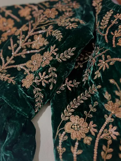 A close-up view of the dense zardosi and sequin work on the sleeve of our green velvet blouse, highlighting the texture and craftsmanship.
