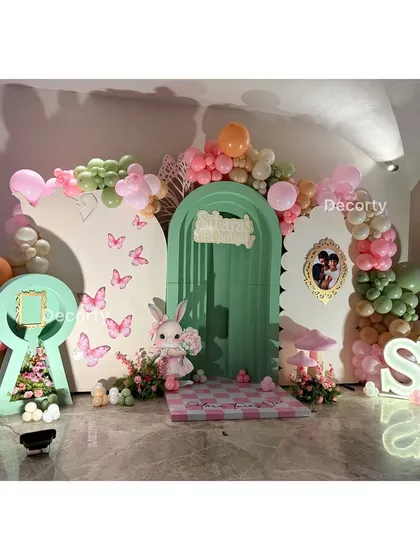 The main backdrop for the "Sitara's Wonderland" party, featuring a keyhole, butterflies, and a cute bunny character.