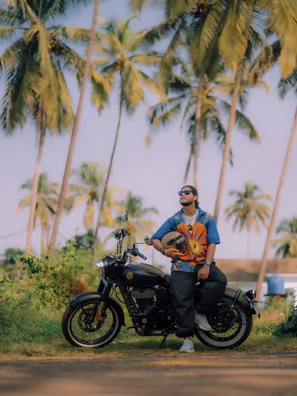 Posing with a black Royal Enfield against a classic Goan backdrop of palm trees. This image showcases the bike's sleek design in a travel context, appealing to riders who love to explore.