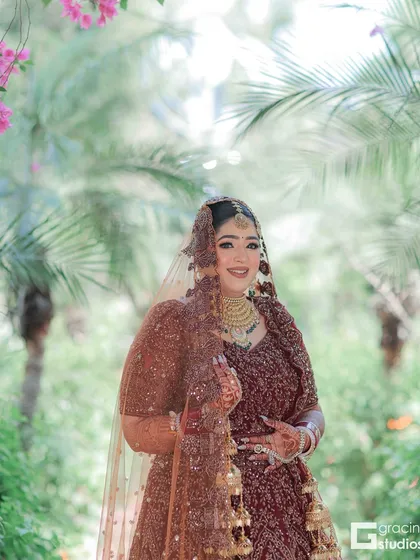 A full-length shot of the bride in a beautiful outdoor setting. The makeup is designed to look natural and radiant.