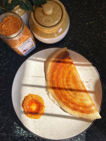 A perfectly made Podi Masala Dosa, golden and crispy, served with a side of our Molgapudi mixed with oil. This image captures the ideal way to enjoy this classic South Indian dish.