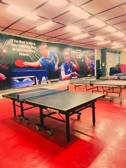 Another angle of our training hall, showcasing the row of tables ready for action. The large mural features table tennis legends, inspiring our players every day.