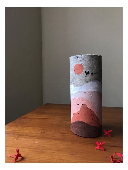 A close-up of the day-themed concrete sculpture. The earthy tones and simple depiction of a sun and birds create a warm, serene feeling. This hand-painted art piece is a perfect example of sustainable home decor.