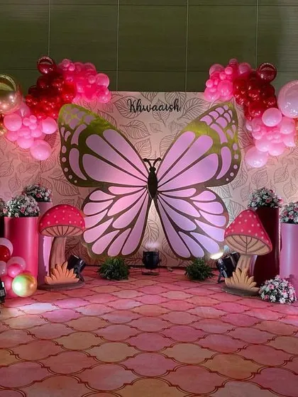 The full view of the enchanting butterfly stage, with dramatic lighting and elegant balloon garlands framing the backdrop.