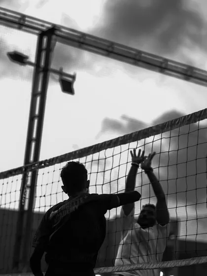 A silhouette of a block at the net, a battle of wills captured in a single, powerful frame.