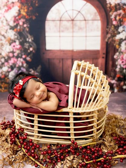 A smile in her sleep. This newborn girl, nestled in a rustic basket, dreams sweet dreams in our floral garden setup.