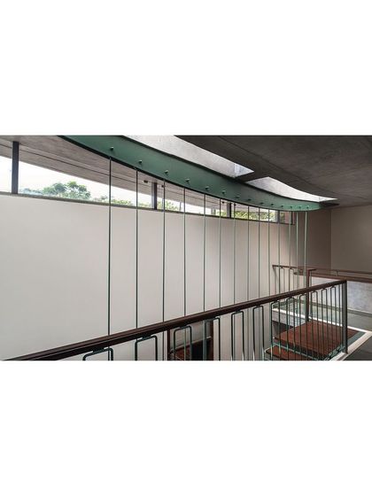 The upper level corridor is designed as a bridge, with a curved steel element tracing the path of circulation. A long clerestory window brings in light while maintaining privacy, and thin steel rods serve as a minimalist, transparent railing.