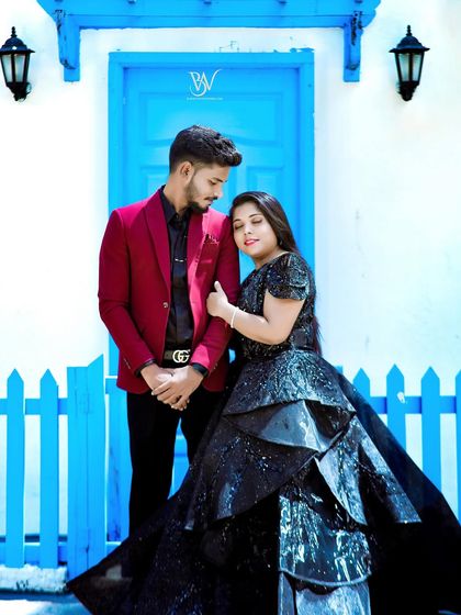 For a more glamorous look, she is in a stunning black tiered gown, and he is in a sharp red blazer. The contrast against the blue door is striking.