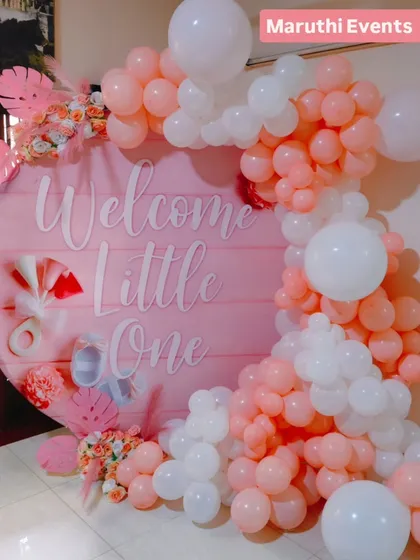 Welcoming a precious little one with this soft and elegant baby shower decor. The round "Welcome Little One" backdrop is framed by a cascade of pink and white balloons, with delicate paper flowers and monstera leaves for a modern, gentle touch.
