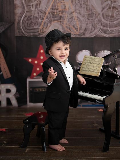 A little rockstar takes the stage. This music-themed setup, complete with a mini piano and a cool suit, is perfect for a future performer.
