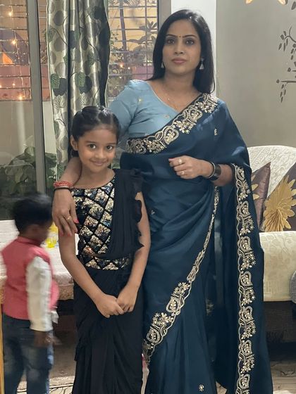 A happy client with her daughter, who is wearing a custom ready-to-wear saree dress in black with beautiful silver embroidery.