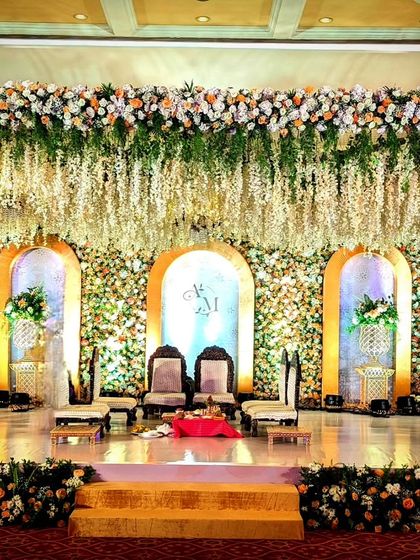 A breathtaking stage with a wall of flowers as the backdrop. Arched niches and a ceiling of hanging white wisteria create a dreamy, romantic setting for a ring ceremony or reception.