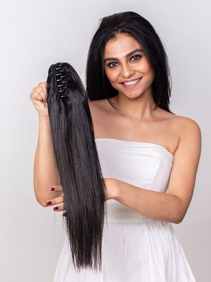 A clutch ponytail is one of the simplest ways to transform your look. Here, the model is holding the easy-to-use clip-in piece, ready to create a stunning hairstyle.