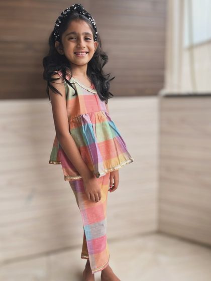 This little girl is all smiles in our colorful checkered peplum top and pants set. It's a perfect example of how my clothes are designed for happy, playful kids.