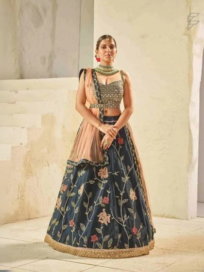 A full view of a unique navy blue lehenga with peach floral embroidery and a matching dupatta. This outfit is perfect for someone who wants a non-traditional color for their event.