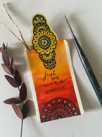 A hand-painted bookmark with a beautiful mandala design and the quote "Just one more chapter!" This is an example of the small, detailed creations from our workshops.