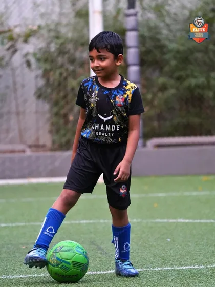 A young player with the ball at his feet, smiling and enjoying the process of learning and improving.