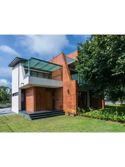 An exterior view of 'An Earthy Affair', a home designed to celebrate natural materials and its connection to the landscape. We used exposed brick and large openings to create a structure that feels rooted and honest. The design plays with solid volumes and open terraces to create a dynamic relationship with the surrounding green space.
