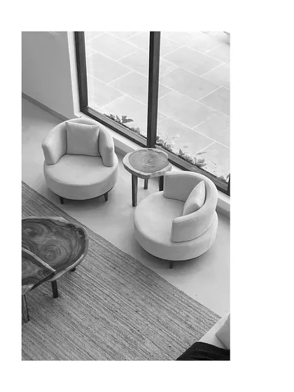 An overhead view of the seating arrangement, showing the organic shapes of the wooden tables and the soft curves of the armchairs. This black and white shot emphasizes form, texture, and the thoughtful composition of the space.