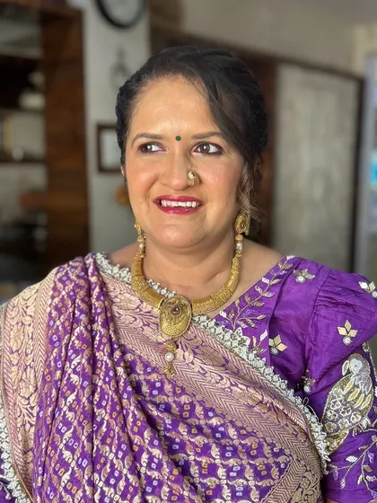 A regal look for a mature client. Her beautiful purple bandhani saree is complemented by a fresh makeup look with a bright lip.