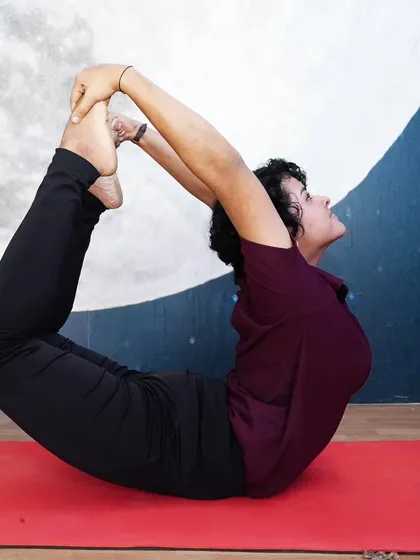 A student holds Dhanurasana (Bow Pose) in front of our moon mural. This pose is a powerful heart opener and strengthens the entire back of the body.