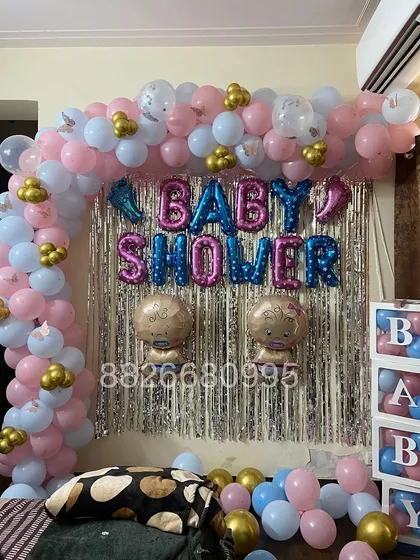 A closer look at the baby shower backdrop, featuring 'BABY SHOWER' foil balloons and cute baby-shaped foils against a shimmering curtain.