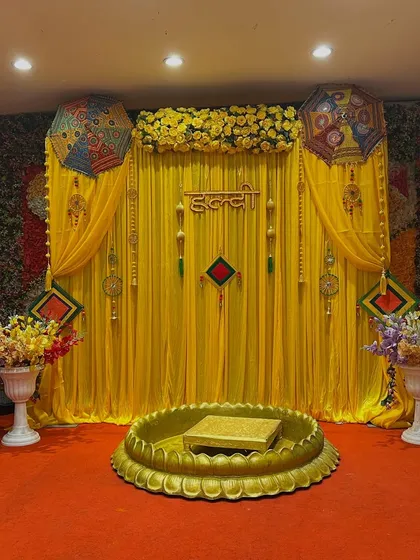 A beautiful Haldi stage with a bright yellow backdrop, traditional umbrellas, and a central lotus bowl, perfect for a classic ceremony.