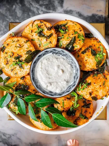 An overhead shot of my gunpowder idli with coconut chutney. The vibrant colors and fresh curry leaves make this dish as beautiful as it is delicious.