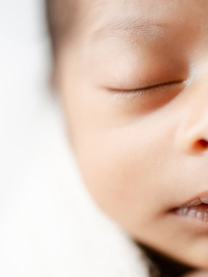 A close-up profile of a newborn's face, highlighting their delicate eyelashes and soft skin.