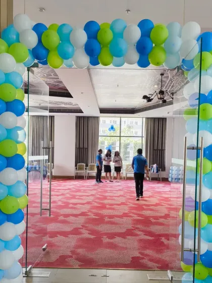 A simple yet effective balloon arch at the entrance of the party hall, using the cricket theme's blue, green, and white colours to welcome guests.