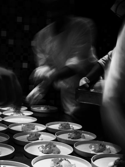 A motion-blur shot of a chef plating, capturing the dynamic and artistic nature of the work.