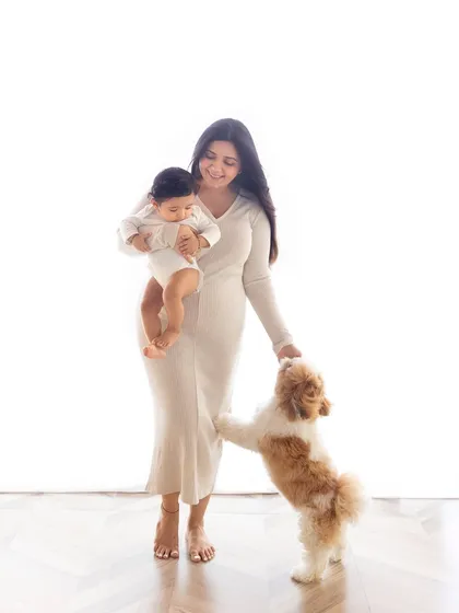 Furry family members are always welcome! A mother holds her baby while their adorable dog looks on, completing the family portrait.
