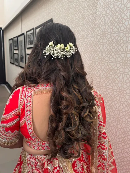 A beautiful half-up style with big, voluminous curls, decorated with a bar of fresh baby's breath. This is a stunning look for a bride on her wedding day.