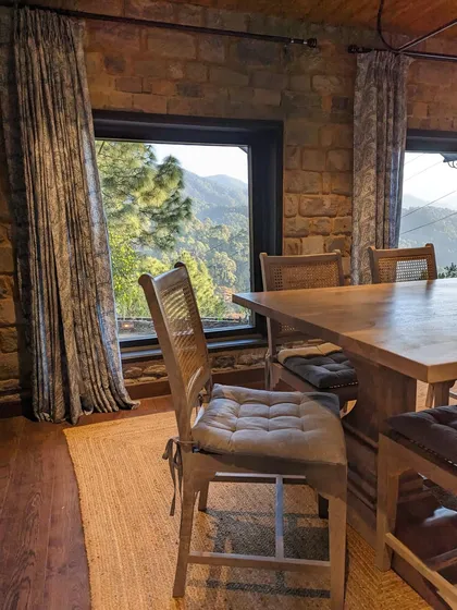 A detail of the dining room, where the window perfectly frames the mountain vista. The simple, rustic furniture allows the natural beauty outside to be the star of the show.