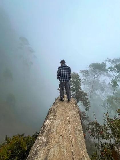 A solo traveler stands at Dolphin's Nose, taking in the vast, misty valley. Our trips are great for solo adventurers looking to join a friendly group.