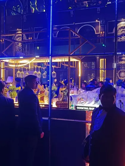 A deep blue, moody lighting scheme for a cocktail event, highlighting the bar's intricate mirrored background and our professional bartenders at work.