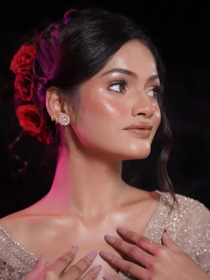 A side profile highlighting the dewy finish on the skin and the elegant floral hair accessory. The glow extends from the face to the neck and shoulders for a seamless look.