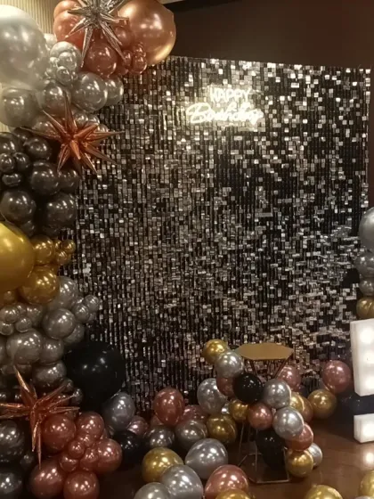 A 50th birthday decoration with a silver shimmer wall and a multi-toned metallic balloon garland. The marquee numbers add a celebratory focal point.