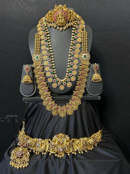 This set features a beautiful combination of a guttapusalu style haaram and a traditional temple choker. The pearl detailing adds a touch of elegance to the antique gold finish.