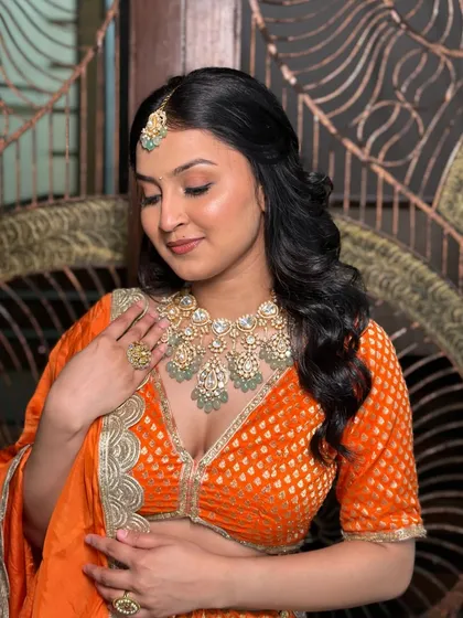 A portrait showcasing the minimal yet impactful glam of this orange lehenga look.