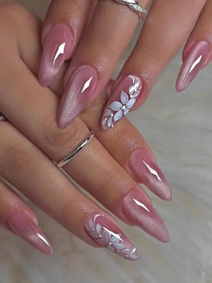 For a soft and romantic bridal style, we created these long, pearlescent pink nails. The look is elevated with a single accent nail on each hand, featuring a beautifully hand-painted white floral design.