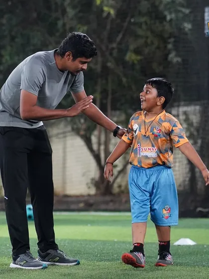A coach shares a light-hearted moment with a young player, showing that training can be fun and motivational.